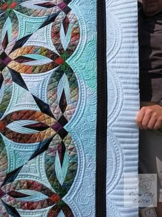 a man is holding up a quilt that has been made into an intricate design on it