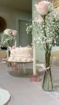 two vases filled with flowers on top of a table next to a white cake