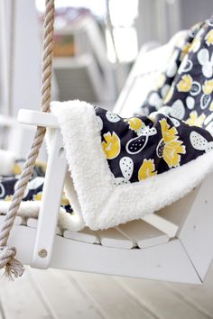 a close up of a white swing chair with yellow flowers on black and white fabric