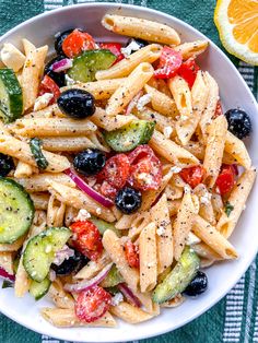 a white bowl filled with pasta salad on top of a green and white table cloth