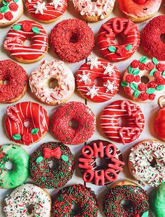 many different donuts with frosting and sprinkles are arranged on a white surface