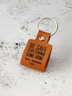 an orange leather keychain with the words home where your feet may leave but not your heart