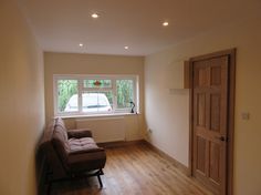 a living room with hard wood flooring and a chair in front of a window