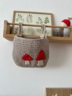 a crocheted purse hanging on the wall next to a shelf with pictures and other items