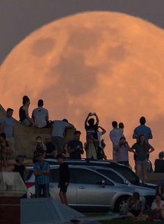 the full moon is seen in the background as people watch