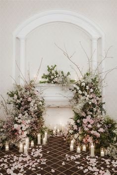 a wedding ceremony with candles and flowers on the floor in front of an arched doorway