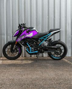 a purple and black motorcycle parked in front of a metal building with blue trim on it