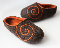 two slippers with orange swirls on them sitting on a white surface next to each other