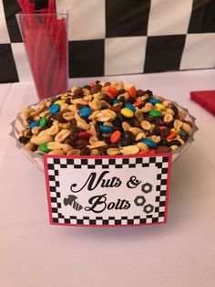 a bowl filled with cereal on top of a table next to a red vase full of candy