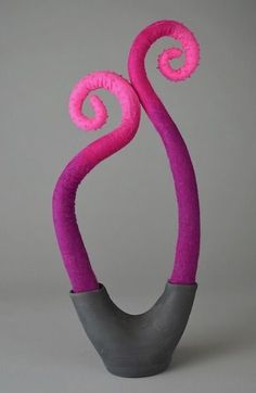 a pink and grey sculpture with two spirals on it's sides, in front of a gray background