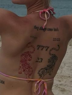 a woman with tattoos on her back at the beach