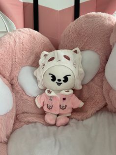 a pink teddy bear sitting on top of a stuffed animal in a baby crib