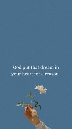 a person holding a flower in their hand with the words god put that dream in your heart for a reason