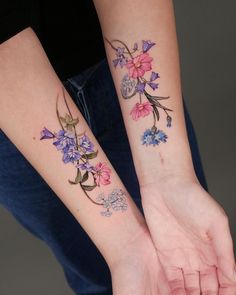 two people with matching tattoos on their arms, both holding each other's hands