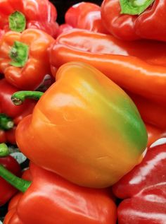 many red and green peppers are stacked together