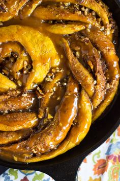 a skillet filled with sliced bananas and caramel sauce on top of a table