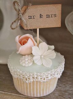 a cupcake decorated with flowers and a sign