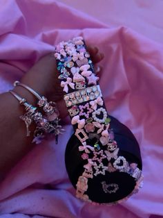 two bracelets that are sitting on top of a pink cloth covered tablecloth, with the word love spelled in white letters surrounded by small flowers