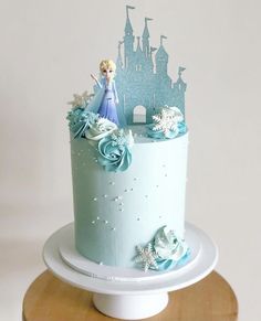 there is a blue cake with a castle on top and snow flakes around it