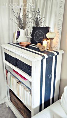 a white book shelf with books on top of it and some candles in front of it