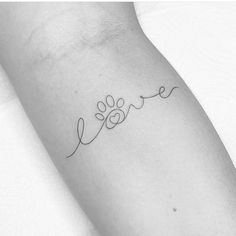 a small dog paw tattoo on the left forearm and right arm with love written in cursive writing