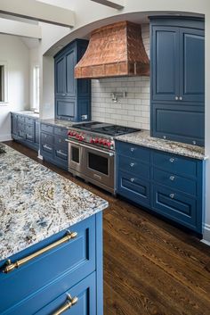 a kitchen with blue cabinets and marble counter tops