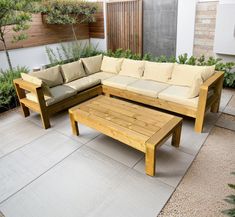 a couch and coffee table sitting on top of a cement floor next to a wooden bench