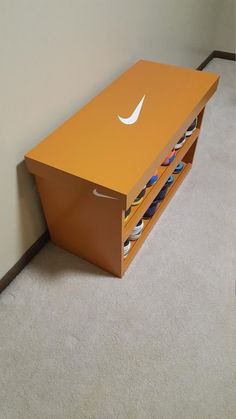 an orange shelf with several pairs of shoes on it next to a white carpeted wall