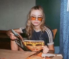 a woman sitting at a table reading a magazine