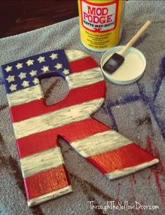 an american flag painted on the letter k with some paint and a brush next to it