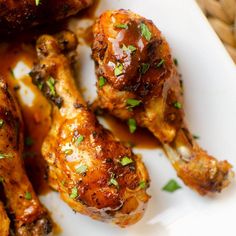 grilled chicken legs covered in sauce and garnished with parsley on a white plate