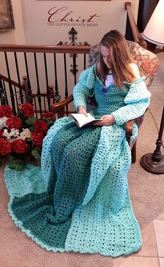 a woman sitting in a chair with a book and flowers on the floor next to her