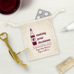 a wine bottle and some corkscrews on a white table with a bag