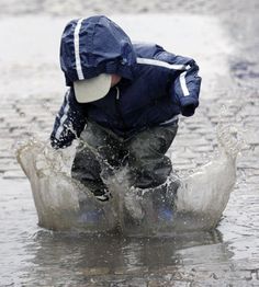 a young boy is playing in the water on his snowboard while wearing a blue jacket and hat