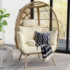 a living room with a rattan swing chair and pillows on the floor next to a potted plant