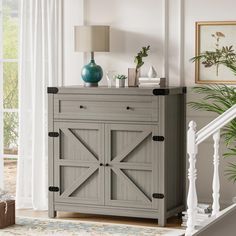 a gray cabinet with doors and drawers in a living room next to a stair case