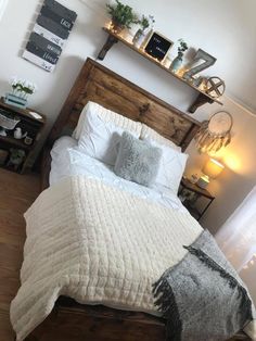 a bed with white sheets and pillows in a bedroom next to a window, wooden headboard