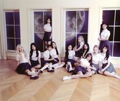 a group of young women sitting next to each other on top of a hard wood floor