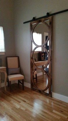 a chair sitting in front of a mirror on top of a hard wood floor next to a window