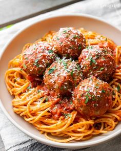 spaghetti and meatballs are served in a white bowl