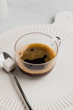 a cup of coffee on a paper plate with a spoon