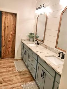 a bathroom with double sinks and two mirrors on the wall next to a wooden door