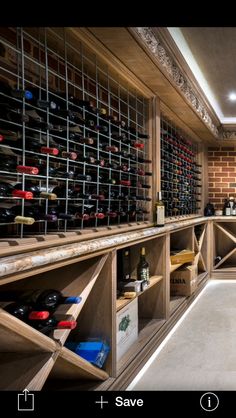 a wine cellar filled with lots of bottles next to a wall covered in wooden shelves