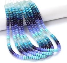 three strands of blue and purple beads on a white surface