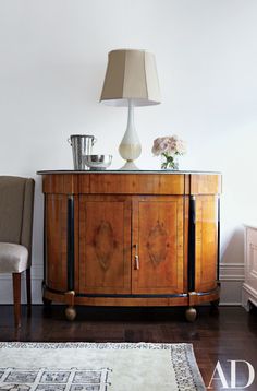 a wooden cabinet sitting on top of a hard wood floor next to a chair and lamp