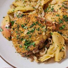 two pieces of chicken with pasta and parsley on a white plate next to a pink towel