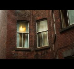 an old brick building with two windows and one light on