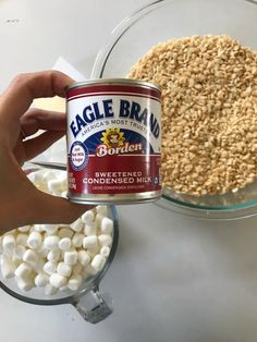 a person holding a can of eagle brand marshmallows in front of a bowl of cereal