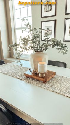 a white vase sitting on top of a table next to a candle and some pictures