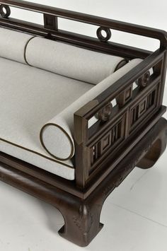 an antique wooden bed with white linens on the bottom and back ends, in front of a white background